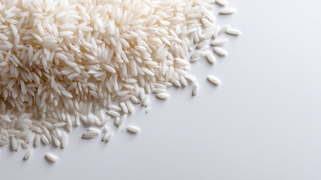 A close-up view of freshly harvested raw white rice grains spilling onto a smooth white surface, highlighting the natural texture for culinary inspiration.の素材