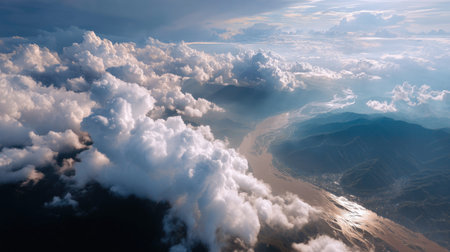 This stunning aerial view captures fluffy clouds above a winding river surrounded by lush mountains, bathed in golden sunlight, evoking tranquility.の素材