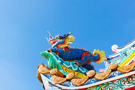 Chinese dragon decoration on the roof against blue skyの写真素材