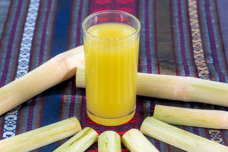 Fresh squeezed sugar cane juice in pitcher with cut pieces cane. Sugar cane juice is placed on a cloth ,の写真素材