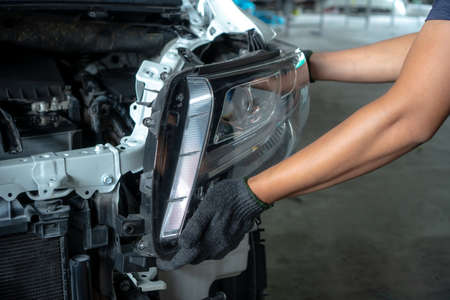 Mechanic with new car headlight in a workshopの写真素材
