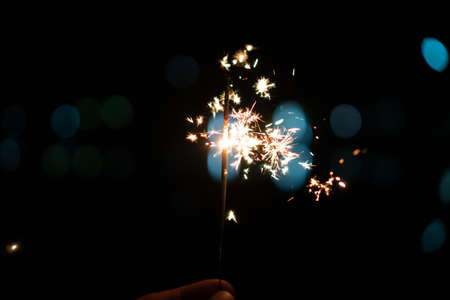 New Year Christmas sparkler on dark background with bokeh lightsの写真素材