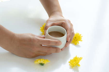 Coffee cup in female hands on a white background.の写真素材