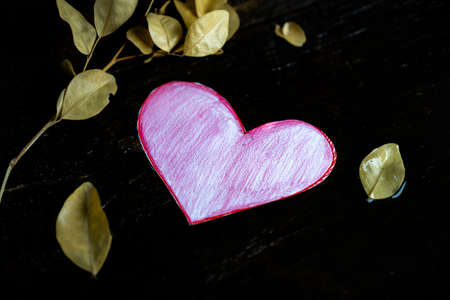 Pink paper heart on a wet wooden table ,And with dead leavesの写真素材