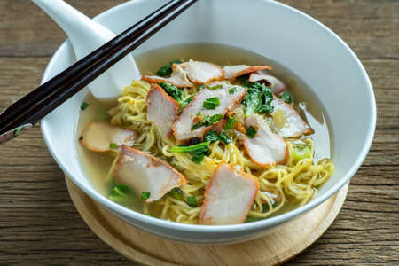 Egg noodle soup with red roast pork ,noodle on wooden background ,Chinese noodle in soupの写真素材