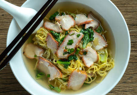 Egg noodle soup with red roast pork ,noodle on wooden background ,Chinese noodle in soupの写真素材