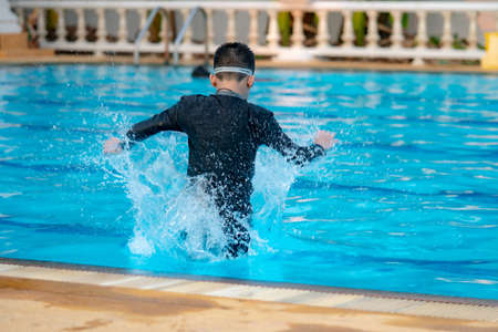 The boys are playing in the pool during the summer.happy boy jumping in the poolの写真素材