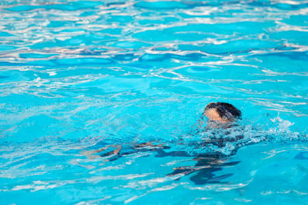 The boys are playing in the pool during the summer..The boy is drowning