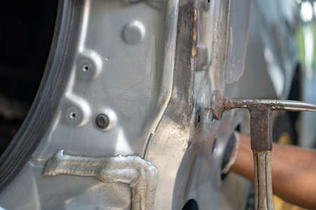 Repairing car dents with a hammer and knock ,Make the surface of the car smooth ,preparing for painting at station service. Worker repairing car bodyの写真素材