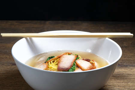 Egg noodle soup with red roast pork ,noodle on wooden backgroundの写真素材