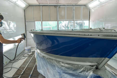 Repairman fixing by painting boat body and painting boat using spray gunの写真素材