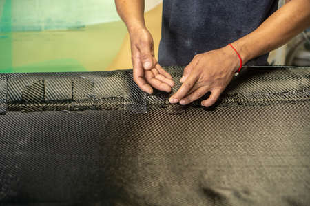 Auto mechanic is making car parts from carbon., The hood (front bonnet ) is made of carbon.