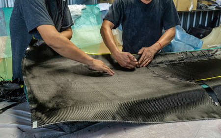Auto mechanic is making car parts from carbon., The hood (front bonnet ) is made of carbon.