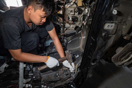 The repairer of the car body uses a hammer to break the damaged iron. ,Auto body repair series : Fixing car bodyの写真素材