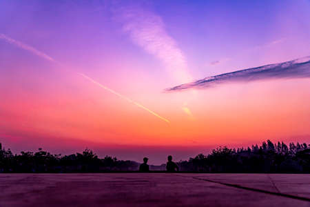 Light from the sun hits the clouds ,Twilight sky and cloud at morning background ,sun shining above black big trees and spires, landscapeの写真素材