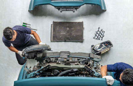 Two repairman mechanics ,Check for damaged cars at the repair station, Maintenance technician is removing the car headlightsの写真素材