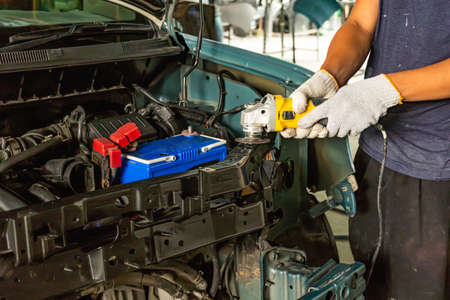 Mechanic worker repairman fixing by sanding polishing car body and preparing for painting at station service.の写真素材