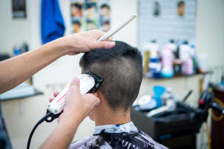 An Asian boy in the barbershop  ,Boy getting haircut by barber in barbershopの写真素材