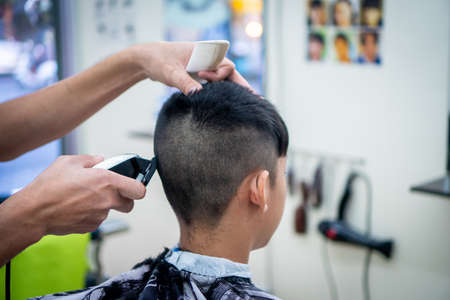 An Asian boy in the barbershop  ,Boy getting haircut by barber in barbershopのeditorial素材