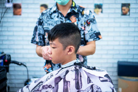An Asian boy in the barbershop  ,Boy getting haircut by barber in barbershopのeditorial素材