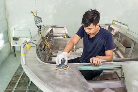 Aluminum boat painting procedure at service center ,The mechanic is using a metal grinder. , Surface...