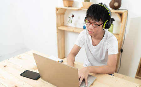 Asian boy student  , Social Distance learning online education during coronavirus epidemic. Cute boy studies and does school homework at home during quarantineの写真素材
