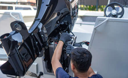 Mechanic is installing speed boat engine , a new engine on an aluminum boat.の写真素材