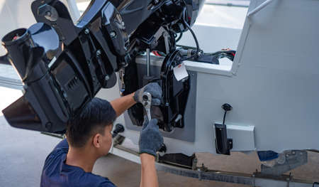 Mechanic is installing speed boat engine , a new engine on an aluminum boat.