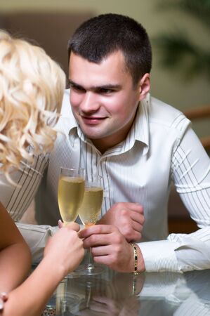 Young couple sharing champagne glasses in a restaurant,  on romantic date. Focus on male の写真素材