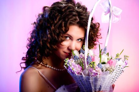 Attractive brunette with a basket of flowers close-upの写真素材