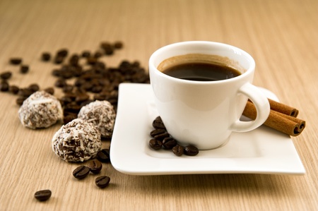 Cup of coffee with beans and truffles over wooden backgroundの写真素材