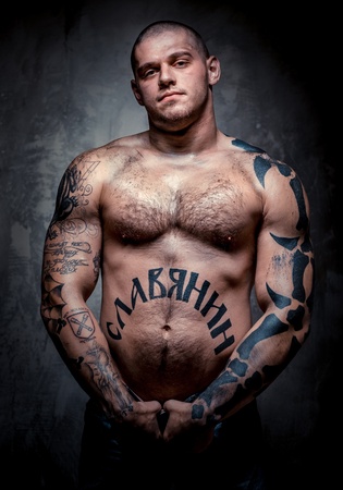 Muscular young man with many tattoos posing over grey backgroundの写真素材