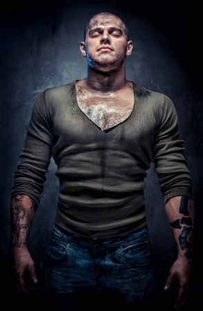 Muscular young man with closed eyes posing indoorsの写真素材