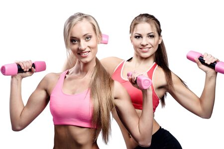 Two beautiful young woman doing fitness exercise with dumbbellsの写真素材