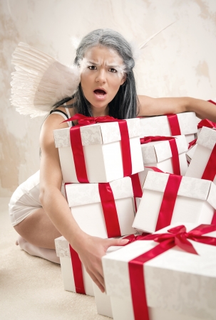 Young woman as angel with heap of gift boxes の写真素材