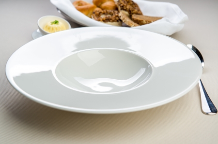 Table settings  Empty white plate with spoon, butter dish and basket with breadの写真素材