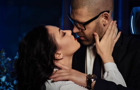 Kissing couple. Portrait of a sensual brunette and handsome businessman. Office romance concept