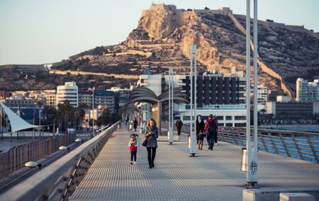 Alicante, Spain-February 24, 2016: People walking on the Alicante pier. View to the Santa Barbara castle. Castle one of the most well-known landmarks in Alicante, and the most visited. Valencian Community, Spainのeditorial素材