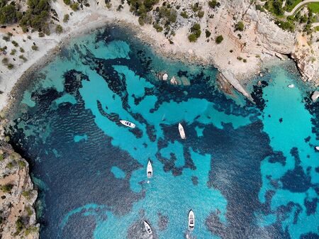 Drone point of view directly from above moored yachts on the bright blue bay on the Cala Blanca Andratx in the Palma de Mallorca, rocky coast breathtaking view, Balearic Islands Spainの写真素材