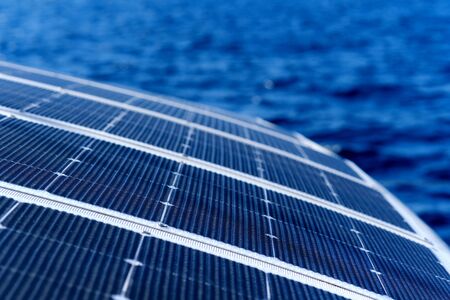 Close up view part of solar panel on dock of sailboat and blue sea waters during sunny day outdoorsの写真素材