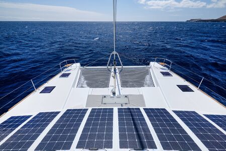 Luxury solar powered catamaran, fully sustainable and powered by solar energy, charging batteries aboard a sailboat, vessel in ocean waters, nobody. Photovoltaic panels renewable eco energy conceptの写真素材