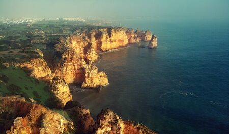 Aerial panoramic image above view of Ponta da Piedade headland with group of rock formations yellow-golden cliffs along limestone coastline, Lagos town, most famous touristic attractions of Portugalの写真素材