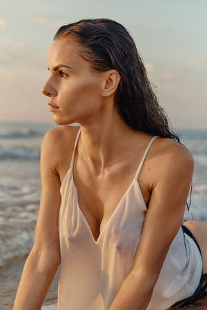 Sexy woman wear white top black panties posing on sea coast. Female looking into distance posing outdoors on the beach during morning. Beauty and fashion conceptの写真素材