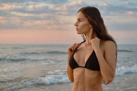 Sexy millennial single woman pose on beach near sea. Beauty and fashion, travel and vacation summer holidays, sexy slim girls with perfect body and summertime collection, fitness bikini model conceptの写真素材