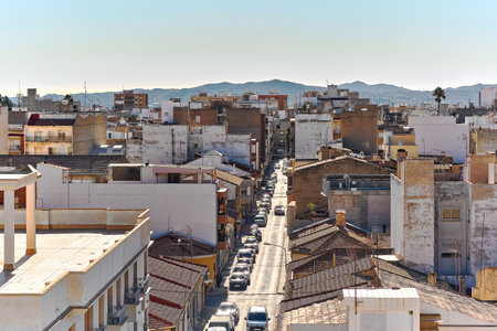 Novelda townscape with mountains view in background. Buildings rooftops, with clear blue skies and the mountainous terrain, typical Mediterranean architecture town, province of Alicante, Spainの写真素材