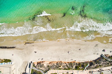 Aerial, drone point of view, beach with turquoise waves gently rolling onto sandy shore, picturesque scene. Torre de la Horadada resort town, province of Alicante, Costa Blanca, Spainの写真素材