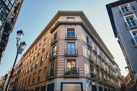 Facade of ancient building located in heart of Zaragoza, features an elegant and historic architectural style with intricate wrought iron balconies, large glass windows, and detailed stonework. Spainの写真素材