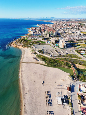 Aerial view Mil Palmeras coastline, showing beachfront houses, promenade, sandy beach and turquoise Mediterranean Sea under clear blue sky, ideal for travel, tourism, real estate.の写真素材