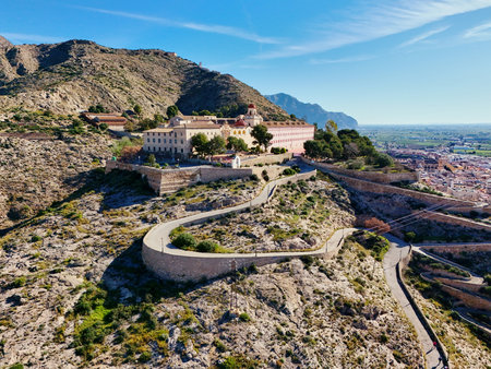 Aerial view of curvy road goes up hill of San Miguel Diocesan Seminary complex atop rugged hill overlooking Orihuela town, Spain. Costa Blanca, province of Alicanteの写真素材