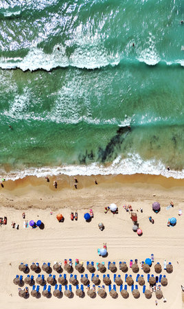 Aerial view of Dehesa de Campoamor beach on Costa Blanca. Straw umbrellas, sandy shoreline, turquoise Mediterranean Sea. Summer holidays, travel, tourism, coastal relaxation. Alicaの写真素材